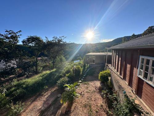 a garden in front of a house with the sun shining at Casa de Madeira in São Lourenço