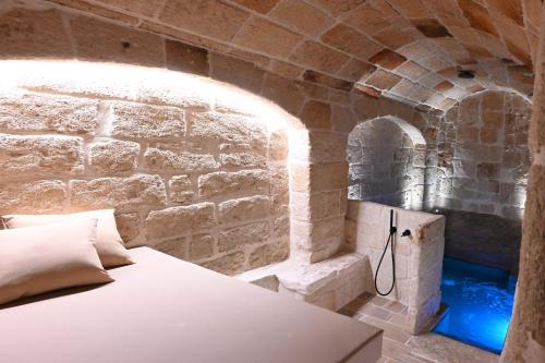 a bedroom with a bed in a stone wall at Dimora Negli Archi in Monopoli