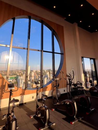 a gym with cardio bikes in front of a large window at Studio 706 Premium no Centro de Chapecó com Piscina Academia e Vaga Garagem AP Completo in Chapecó