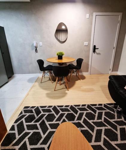 a table and chairs in a living room with a rug at Studio 706 Premium no Centro de Chapecó com Piscina Academia e Vaga Garagem AP Completo in Chapecó
