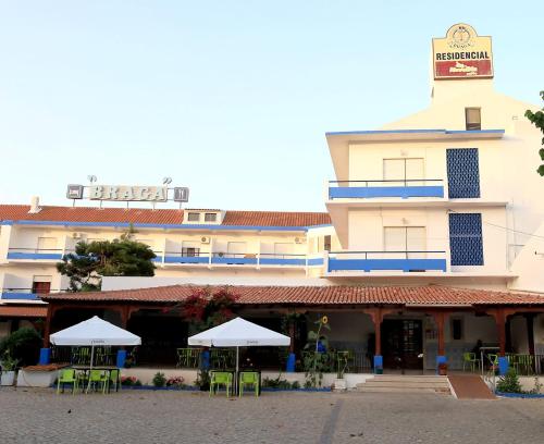 a hotel with tables and umbrellas in front of it at Residencial Braga in Vimeiro