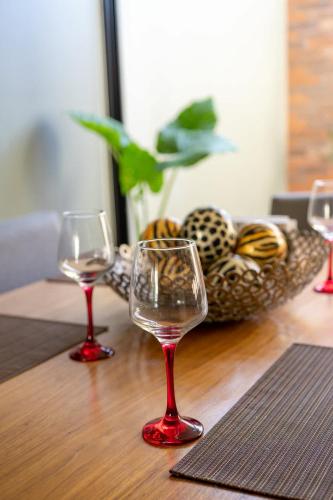 two wine glasses on a wooden table with a basket of bread at Residencia Galicia Family in Guadalajara