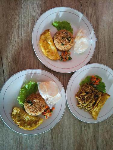 tres platos de comida en una mesa de madera en Casa De' Summer Banyuwangi, en Banyuwangi
