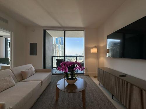 a living room with a couch and a table with flowers on it at Downtown Miami view - 38th floor gem in Miami