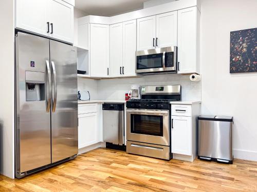 a kitchen with stainless steel appliances and white cabinets at The Chauncey Homestay in Brooklyn