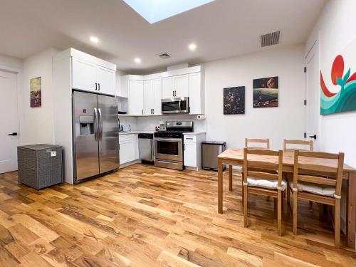 a kitchen with white cabinets and a wooden table with chairs at The Chauncey House in Brooklyn