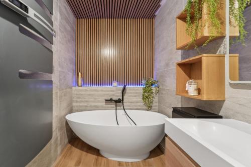 Un baño con bañera blanca y lavabo. en Appartement Design Porte de Paris avec parking, en Sèvres