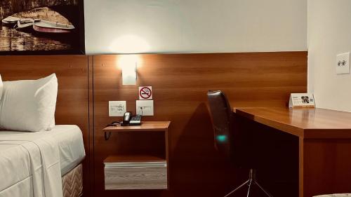 a bedroom with a desk and a bed and a desk with a chair at Hotel Amsterdam Montes Claros in Montes Claros