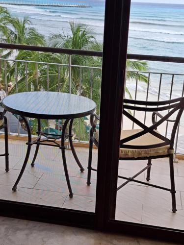 a table and chair on a balcony with a view of the beach at Beach Front - Ocean View 1 BR Condo w Terrace & Hughe Infinity Pool Heart of Playa del Carmen in Playa del Carmen