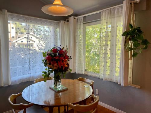 een eettafel met een vaas met bloemen erop bij Cozy Beach Bungalow- Happynest in Long Beach