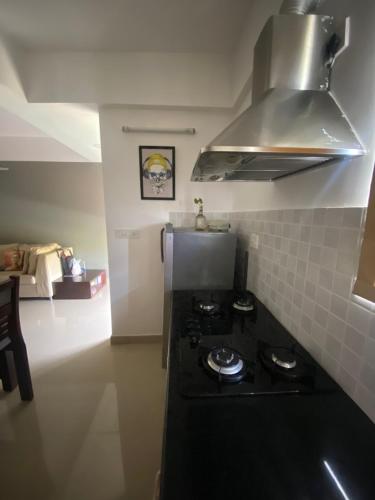 a kitchen with a black stove top oven next to a refrigerator at Calm and Cosy 1bhk in Thiruvananthapuram in Trivandrum
