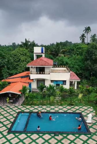 a building with a swimming pool in front of a house at Vana Serene Villa in Ambepur