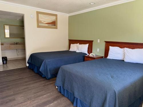 a hotel room with two beds and a bathroom at Regency Inn Fresno in Fresno