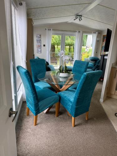 a dining room with blue chairs and a glass table at Riverbank Lodge in Stratford-upon-Avon