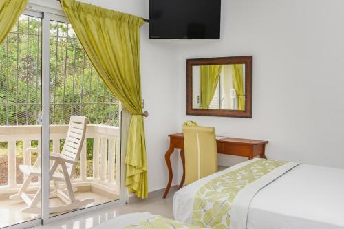 a bedroom with a bed and a desk and a window at Hotel Restaurant Chino in Santa Bárbara de Samaná
