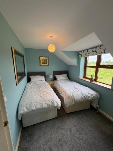 two beds in a bedroom with blue walls and a window at Modern Country Loft, Ballymena in Teeshan