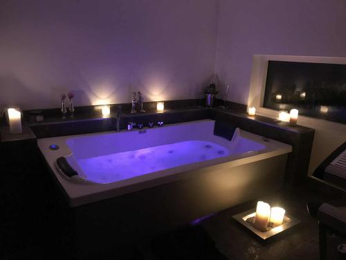 a bathroom with a large tub with candles and lights at Roskabende og idyllisk oase in Ebeltoft