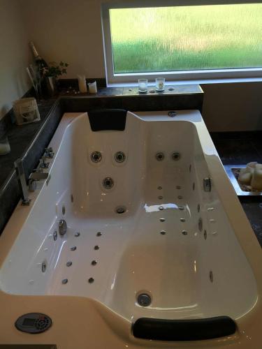 a large white bath tub in a bathroom at Roskabende og idyllisk oase in Ebeltoft