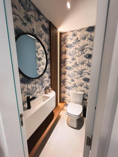 a bathroom with a toilet and a mirror at Apê elegante, terraço Lindo e ótima localização in Capão da Canoa