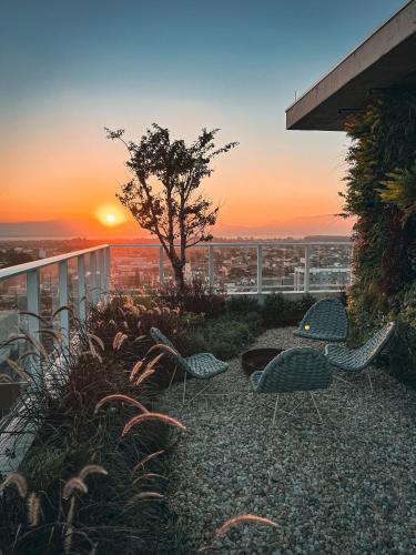two chairs and a tree on a balcony with the sunset at Apê elegante, terraço Lindo e ótima localização in Capão da Canoa