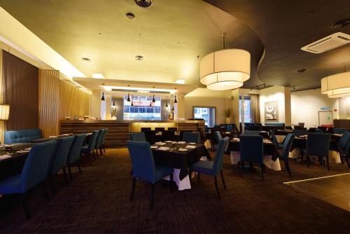 a dining room with tables and blue chairs at Abell Hotel in Kuching