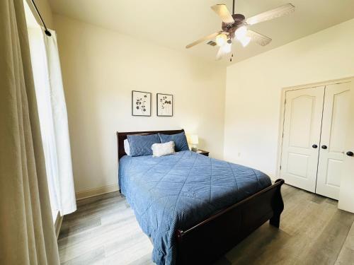 a bedroom with a bed with a blue comforter and a ceiling fan at Chateau 8 in Hammond