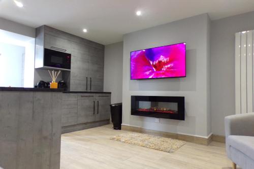 a living room with a fireplace and a tv on the wall at 4 The Dome, Barton on sea - Where Comfort Meets the Coast in Barton on Sea