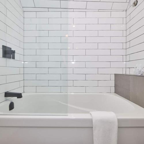 a white bathroom with a bath tub with a towel at Riverside Stay in Niagara Falls