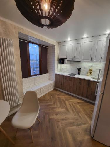 a kitchen with white cabinets and a table and a chair at Апартаменты 2 in Karagandy