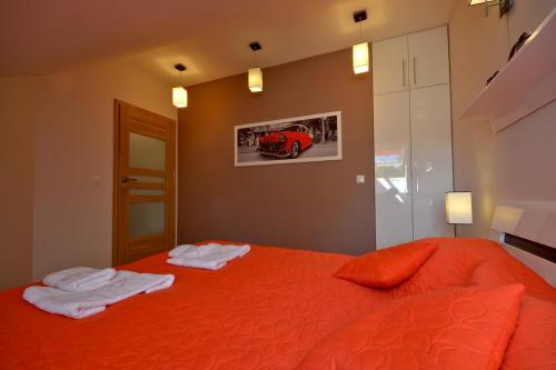 a bedroom with an orange bed with two towels on it at StaraPolana.EU & SPA in Zakopane