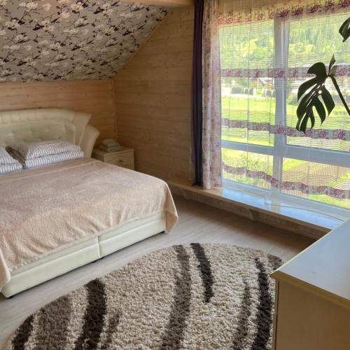 a bedroom with a bed and a large window at Едем in Verkhovyna