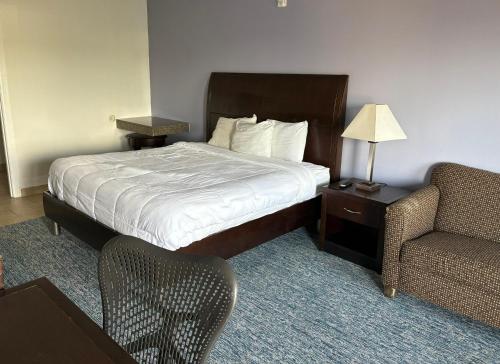 a hotel room with a bed and a chair at Westwood Inn Extended Stay by OYO Gonzales TX in Gonzales
