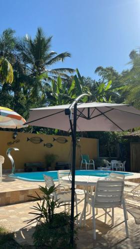 an umbrella and chairs next to a swimming pool at Chalé 400m Praia e Cachoeiras com Piscina Quente e Wifi in São Sebastião