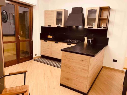 a kitchen with a black counter top and wooden cabinets at Nuovissimo appartamento moderno con box auto in Sassari