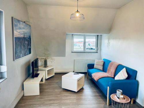 Una sala de estar con un sofá azul y un televisor. en Gravelines Beach Apartment, en Gravelines