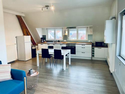 Una cocina con gabinetes blancos y una mesa y sillas. en Gravelines Beach Apartment, en Gravelines
