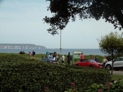 a group of people standing around cars parked next to the water at 4 The Dome, Barton on sea - Where Comfort Meets the Coast in Barton on Sea