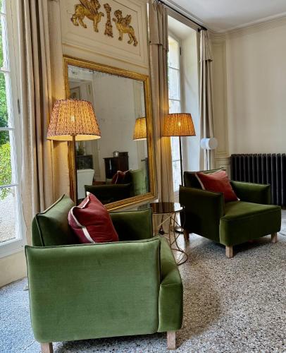 a living room with two green chairs and a mirror at Château Saint Perret in Avignon