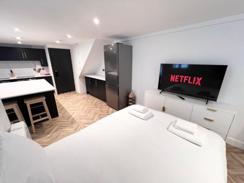 a white room with a television and a kitchen at Eleven on Dragon - Boutique Hotel Rooms & Studio Apartment in Harrogate