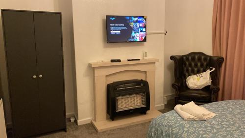 a room with a fireplace and a tv and a chair at Olivetem Comfort House in Bolton