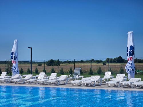 a row of chairs and umbrellas next to a pool at Hotel Helikon in Yanoshi