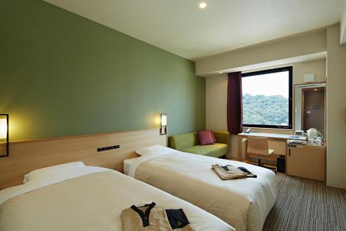 a hotel room with two beds and a window at Candeo Hotels Matsuyama Okaido in Matsuyama