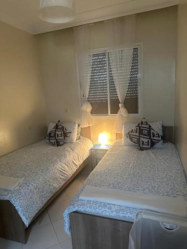 a bedroom with two beds and a lamp in it at Apprt 2min de la Gare,Wi-Fi Fibre, Netflix ,PS4 in Settat