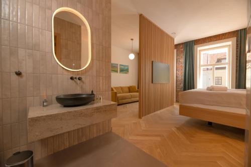 a bathroom with a sink and a bed and a mirror at 1779 SUITES Kežmarok in Kežmarok