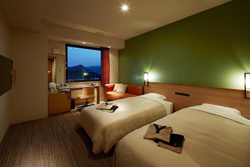 a hotel room with two beds and a window at Candeo Hotels Matsuyama Okaido in Matsuyama