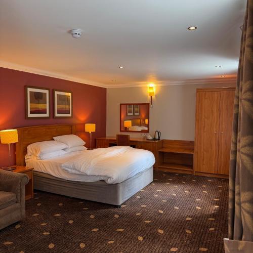 a bedroom with a bed and a couch and a chair at Plas Derwen Hotel in Abergavenny