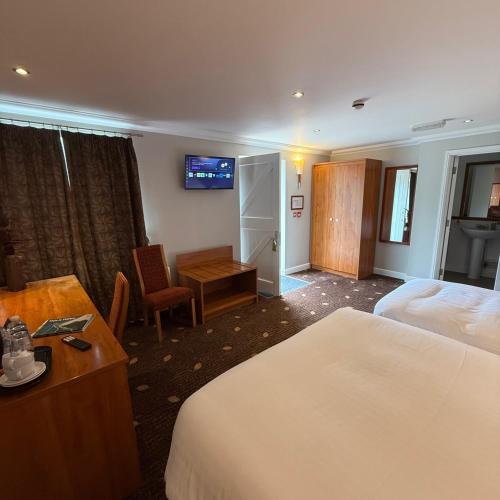 a hotel room with two beds and a desk at Plas Derwen Hotel in Abergavenny