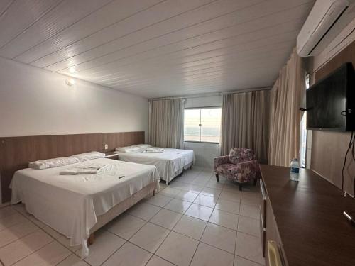 ein Hotelzimmer mit zwei Betten und einem Fernseher in der Unterkunft Juscelino Pousada lazer in Tibau