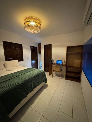 a bedroom with a bed and a desk with a television at Pousada Amazing Jeri in Jericoacoara