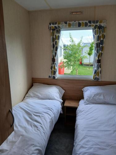 two beds in a small room with a window at Lexi's Lodge in Tattershall
